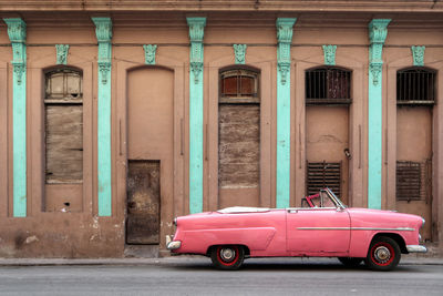 Red vintage car on street against building