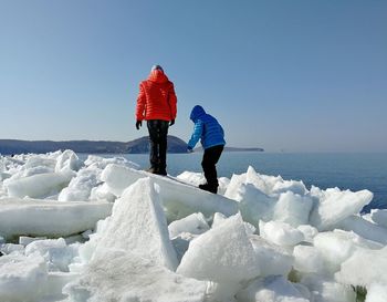 Siblings standing on ice at beach