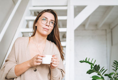 Portrait of young woman standing against wall