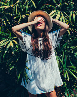 Young woman standing against plants