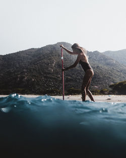 Side view of senior woman in water against sky