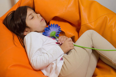 High angle view of girl holding flower while sleeping on bean bag