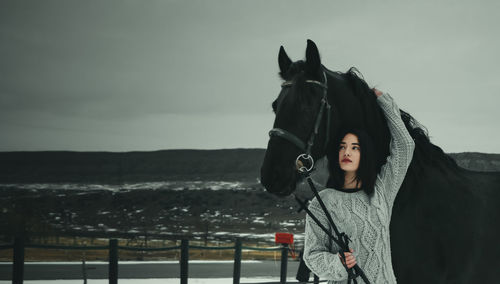 Portrait of woman standing by railing against sky during winter