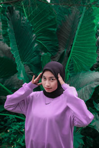 Young woman standing against pink plants