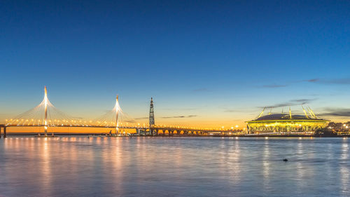 Illuminated bridge over river against blue sky