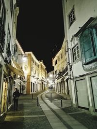 People walking on street amidst buildings in city at night