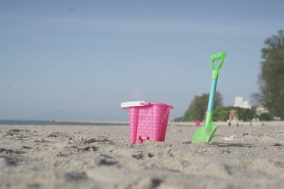 Bucket and shovel at sandy against sky