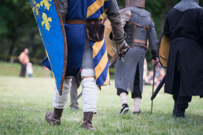 Low section of knights in armor walking on field