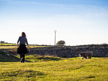 Full length of mature woman playing with dog on grass