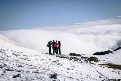 Rear view of people on snowcapped mountain against sky