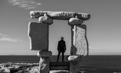 Rear view of man standing by sea against sky