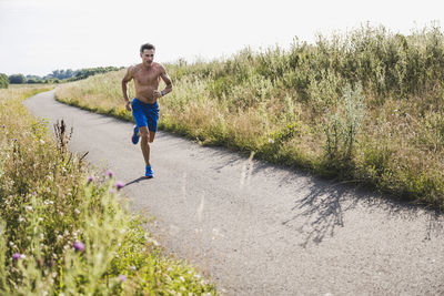 Shirtless male athlete running on road