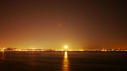 Illuminated sea against sky at night