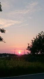 Silhouette trees on landscape against sky at sunset