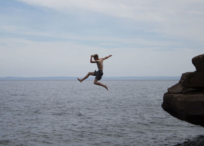 Full length of man jumping in sea against sky