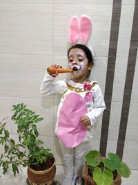 Girl holding pink while standing on potted plant