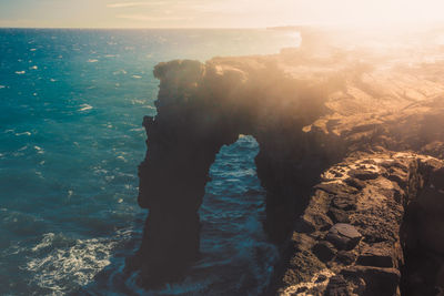 Rock formation by sea against sky during sunset