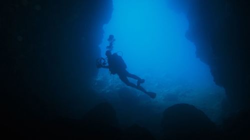 Silhouette person scuba diving undersea