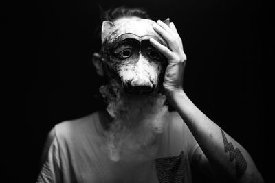 Close-up portrait of man with hand on black background