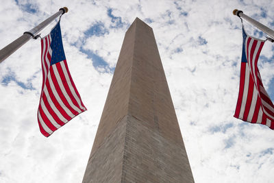 Low angle view of flags against cloudy sky