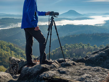 Outdoor travel photographer journalist holding dslr camera in mountain background. environment theme