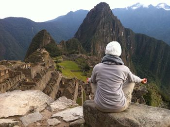 Rear view of woman sitting on rock at machu picchu