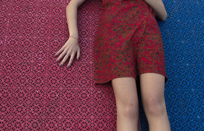 Midsection of young woman lying on carpet