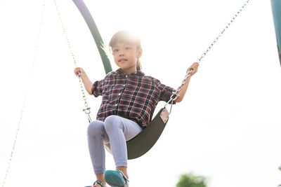 Boy sitting on swing at playground