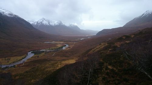 Scenic view of river and mountains against cloudy sky