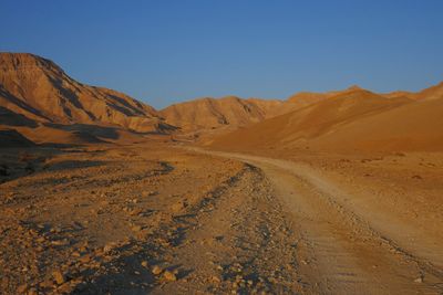 Scenic view of desert against clear blue sky