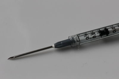 Close-up of syringe over white background