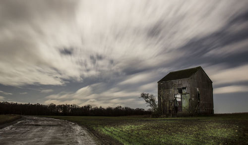 View of field against cloudy sky