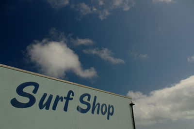 Low angle view of information sign against cloudy sky