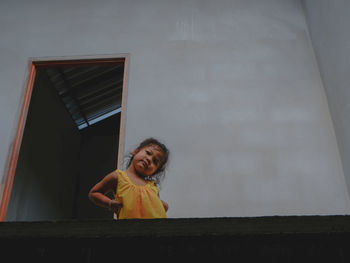 Portrait of smiling girl standing against wall