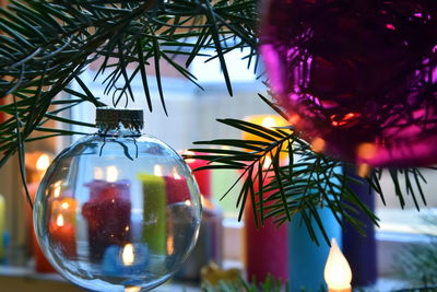Multicolored christmas tree balls and multicolored candles in background 