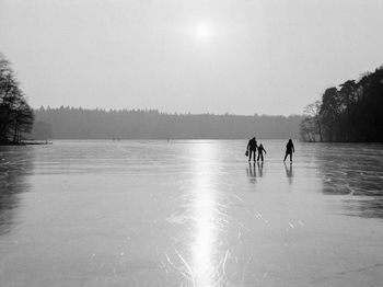Family on frozen lake against sky 