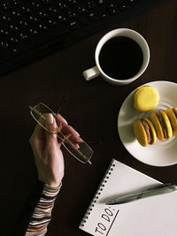 High angle view of hand holding coffee cup on table