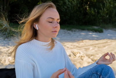 Happy young woman on the beach sea ocean. wearing wireless headphones doing audio healing sound
