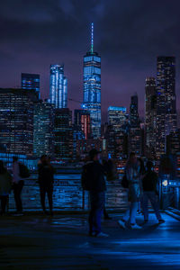 People at illuminated modern buildings in city at night