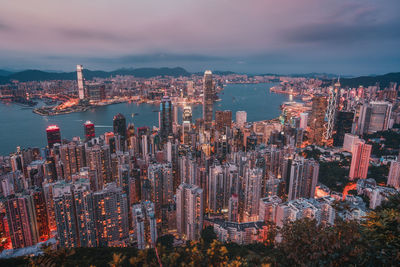 Aerial view of city at waterfront against cloudy sky