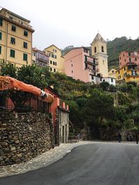 Road by buildings against clear sky