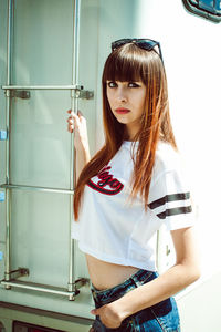 Portrait of young woman standing by camper trailer