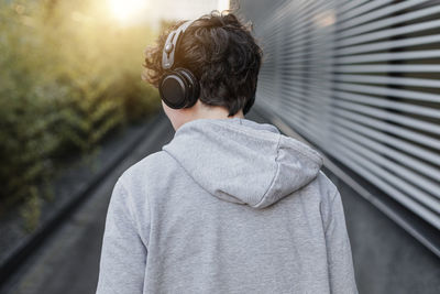 Rear view of teenage boy standing against built structure