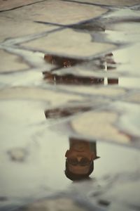 Reflection of man in puddle on lake