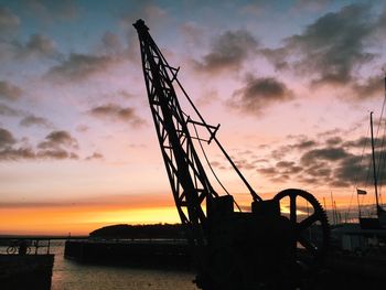 Silhouette cranes against sky during sunset