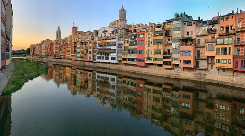 Buildings by river against sky in city