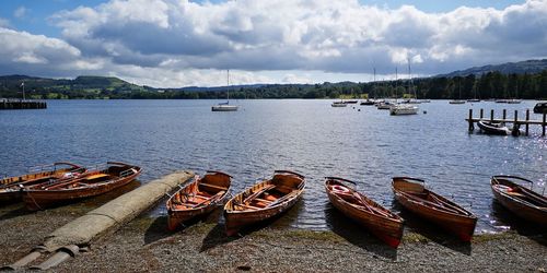 Sailboats moored in lake against sky