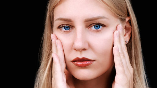 Close-up portrait of young woman against black background