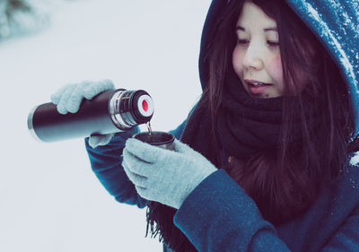 Close-up of woman with thermos in snow