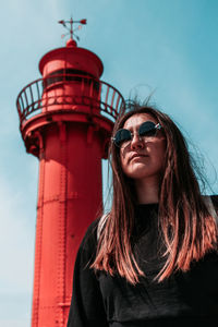 Low angle view of woman wearing sunglasses while standing against tower